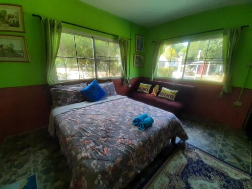 a bedroom with a bed with a blue teddy bear on it at Titanic Park in Ratchaburi