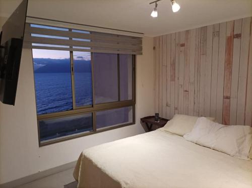 a bedroom with a bed and a large window at Departamento Antofagasta. Playa privada in La Chimba