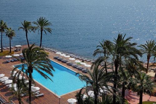 an aerial view of a swimming pool with palm trees and the ocean at Palace Bonanza Playa Resort & SPA by Olivia Hotels Collection in Illetas