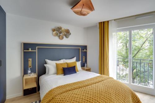 1 dormitorio con 1 cama con almohadas amarillas y azules en Séjours Parisiens / Suite Étoile / 5*, en París