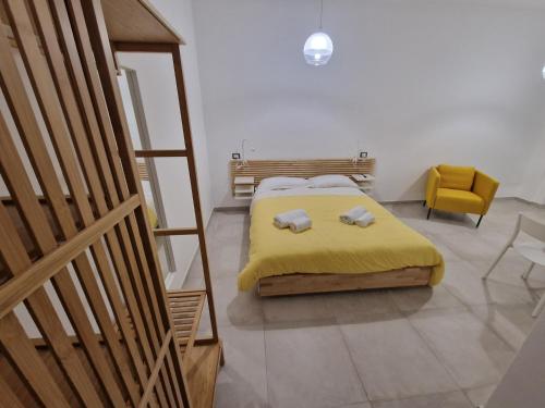 ナポリにあるNeapolitan Skyscraper Suitesのベッドルーム1室(黄色い毛布と黄色い椅子付きのベッド1台付)