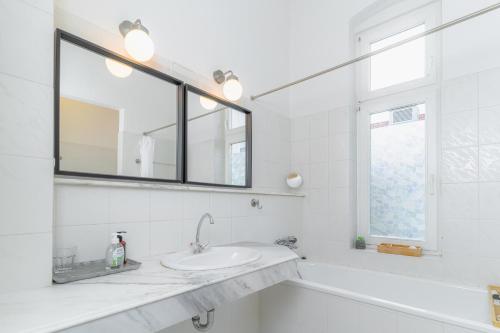 une salle de bains blanche avec un lavabo et un miroir dans l'établissement Hansekoje direkt an der Hafenspitze, à Flensbourg