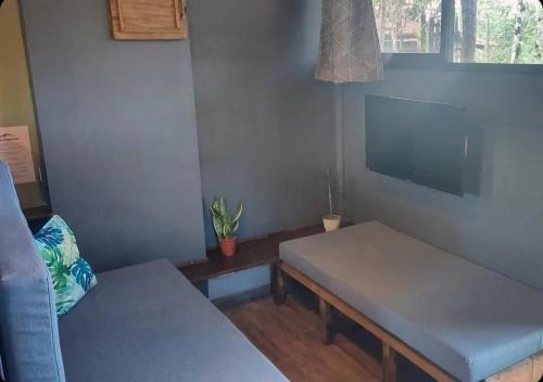 a living room with two benches and a flat screen tv at Cabañita La Montaña de Las Brisas in San Vito