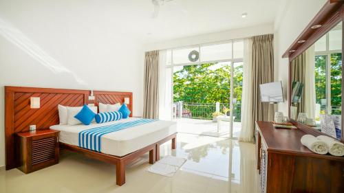a bedroom with a bed and a desk and a window at Weleges Place in Hikkaduwa