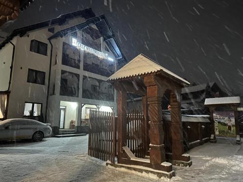 a building with a gazebo in the snow at Casa Maramureșană in Vişeu de Sus