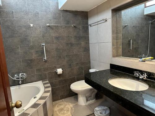a bathroom with a tub and a toilet and a sink at Habitacion doble vista a la Huaca Miraflores in Lima