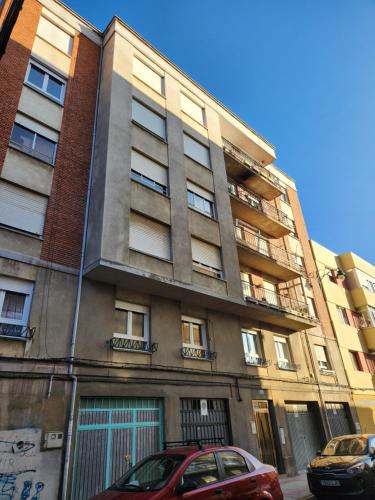 un edificio de apartamentos con un coche rojo estacionado frente a él en Moderno Apartamento Cerca del centro en León en León