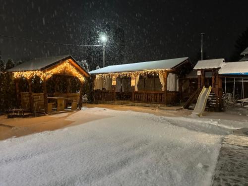 a building with christmas lights on it in the snow at Casa Maramureșană in Vişeu de Sus