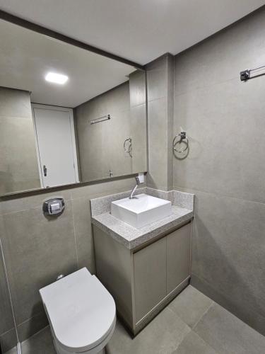 ein Badezimmer mit einem Waschbecken, einem WC und einem Spiegel in der Unterkunft Apartamento Quadra Mar ST Balneário Camboriú in Balneário Camboriú