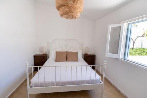 a white bed in a white room with a window at Buona Onda in Siracusa