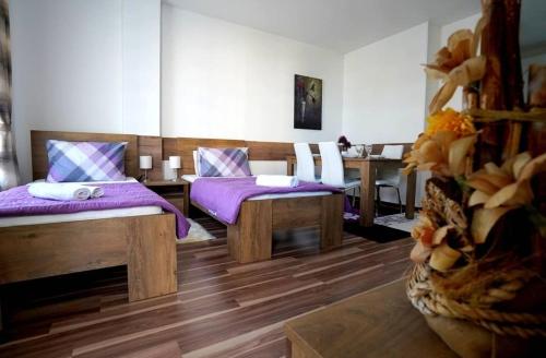 Habitación con 2 camas con cojines morados y mesa. en Serbona apartment en Kladovo