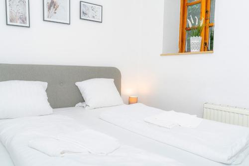 uma cama branca com lençóis e almofadas brancos em Smutjes Koje, mittendrin und doch am Meer em Flensburg