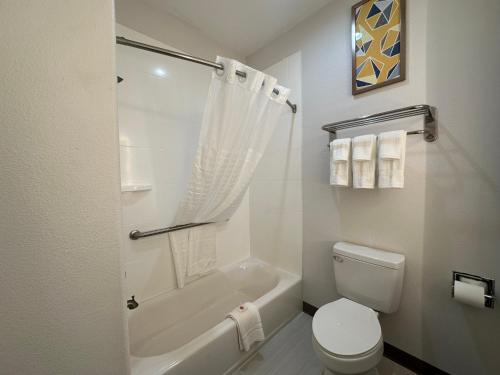 a bathroom with a toilet and a tub and a sink at Comfort Inn & Suites in Schulenburg