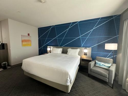 a bedroom with a large bed and a chair at Comfort Inn & Suites in Schulenburg