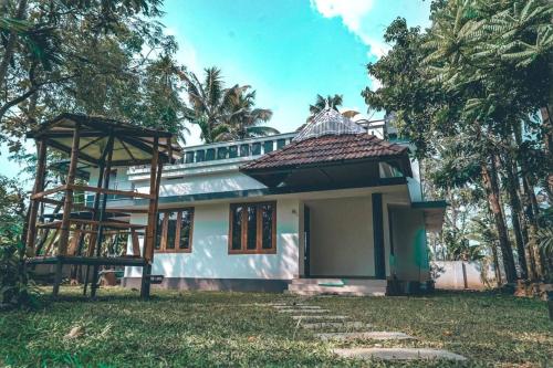 una pequeña casa blanca con techo en Paddy N Pond Tree house Villa 2R, en Angamaly