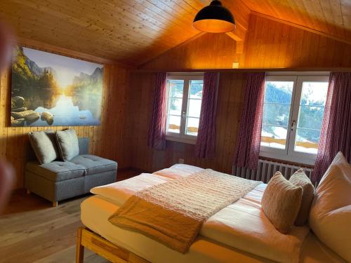 a bedroom with a bed and a couch and windows at Jägerstübli Grindelwald in Grindelwald