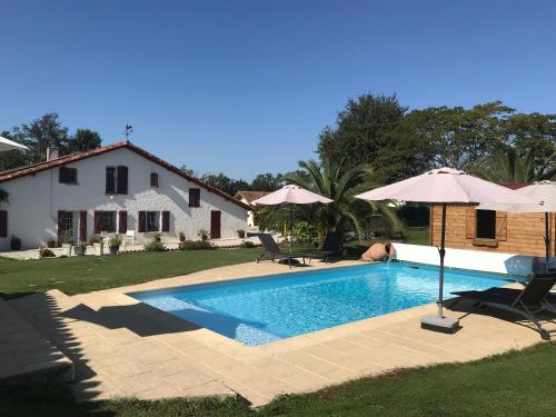 a swimming pool with two umbrellas and a house at la forge de Clermont in Clermont