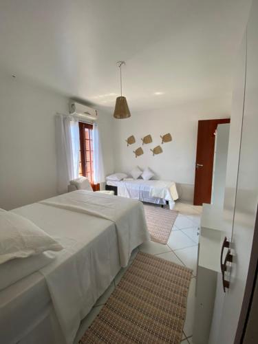 Dieses weiße Zimmer verfügt über 2 Betten und ein Fenster. in der Unterkunft Quintal da Casa in Garopaba