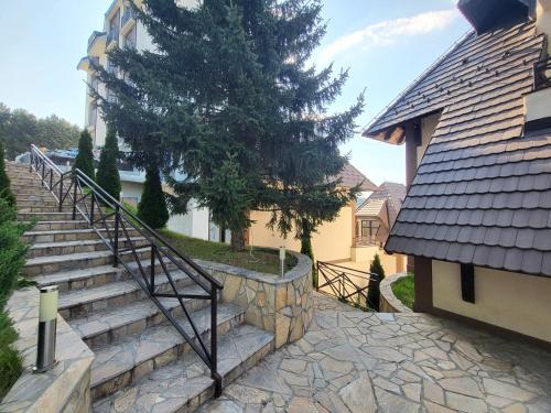 a set of stairs next to a house with a tree at Apartmansko naselje DVORI in Kopaonik