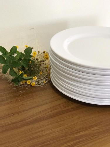 a stack of white plates on a table with a plant at Faith Home 3 in Arraial do Cabo