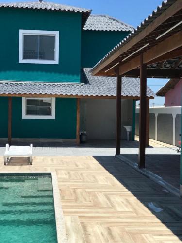 a blue house with a swimming pool in front of it at Faith Home 3 in Arraial do Cabo
