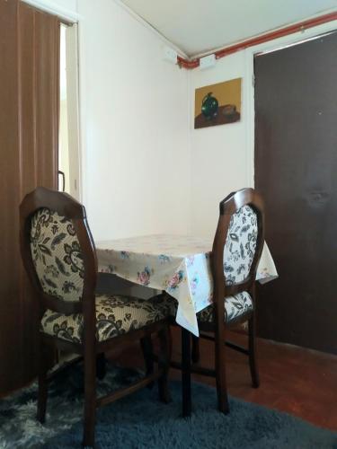 a dining room table with two chairs and a table with a cloth at Alojamiento para 1 sola persona Dpto independiente muy tranquilo in Valdivia