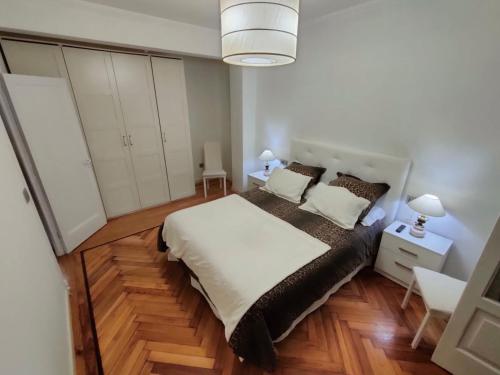 a bedroom with a large white bed and wooden floors at Vintage House in Vigo