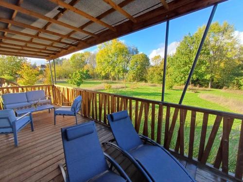 a deck with chairs and a couch and a table at Les Chalets du Moulin de Valade in Condat-sur-Trincou
