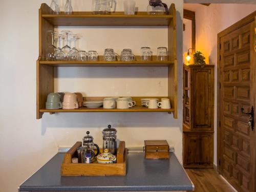 a kitchen with a shelf with glasses and a tea pot at La cabaña del Burguillo in El Barraco