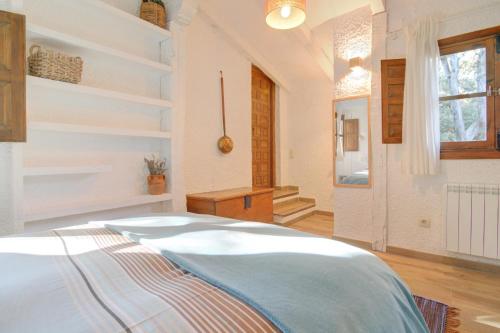 a white bedroom with a bed and a window at La cabaña del Burguillo in El Barraco