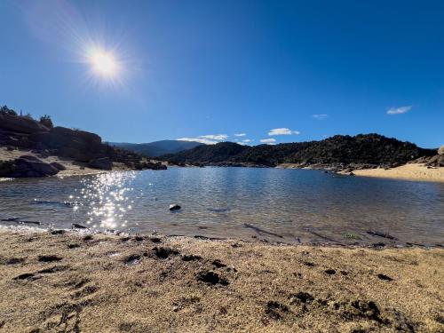 a body of water with the sun in the sky at La cabaña del Burguillo in El Barraco