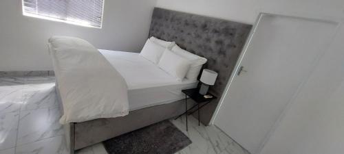 Dormitorio pequeño con cama con sábanas y almohadas blancas en Walvis Bay Staycation en Walvis Bay
