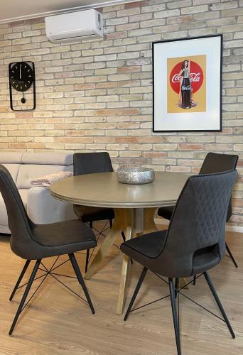 a table and chairs in a room with a brick wall at Cityluxandloft 2 Bestern in Szeged