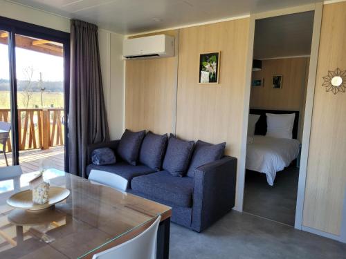 a living room with a blue couch and a bed at Les Chalets du Moulin de Valade in Condat-sur-Trincou