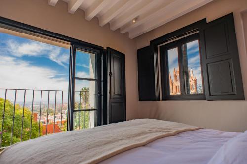 een slaapkamer met een bed en een groot raam bij Suite de Lujo con Terraza Panorámica in San Miguel de Allende