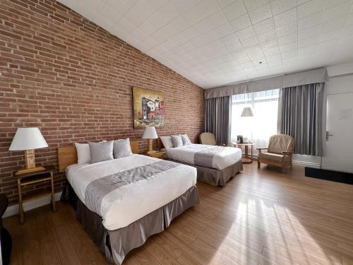 ein Hotelzimmer mit 2 Betten und einer Ziegelwand in der Unterkunft Hotel La Caravelle in Baie-Comeau