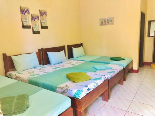 two twin beds in a room at JBR Tourist Inn - Port Barton in Itaytay
