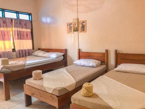 a room with three beds and a window at JBR Tourist Inn - Port Barton in Itaytay