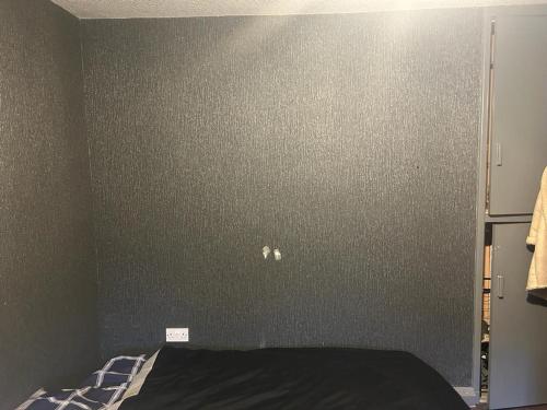 a bedroom with a gray wall with a bed at Heywood in Heywood