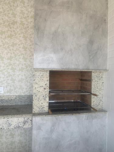 a stone fireplace with a wooden shelf on a wall at Faith Home 3 in Arraial do Cabo