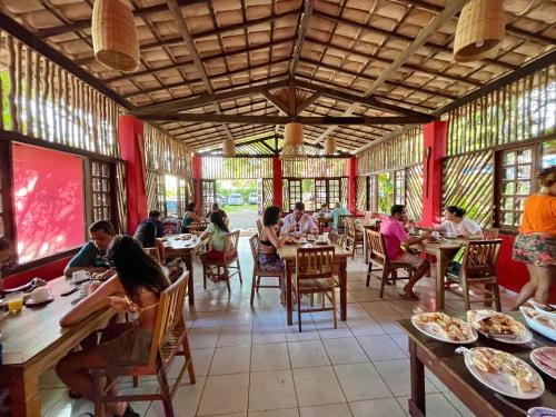 a group of people sitting at tables in a restaurant at Pousada Canto do sabiá Imbassaí in Imbassai