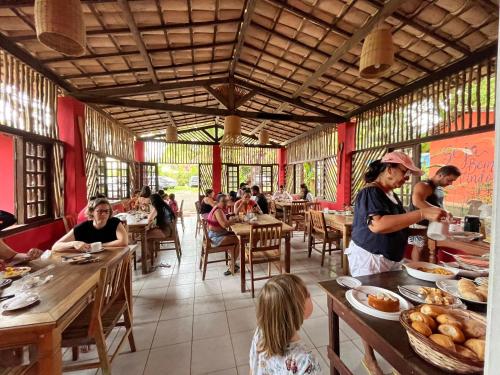 grupa ludzi siedzących przy stolikach w restauracji w obiekcie Pousada Canto do sabiá Imbassaí w mieście Imbassai
