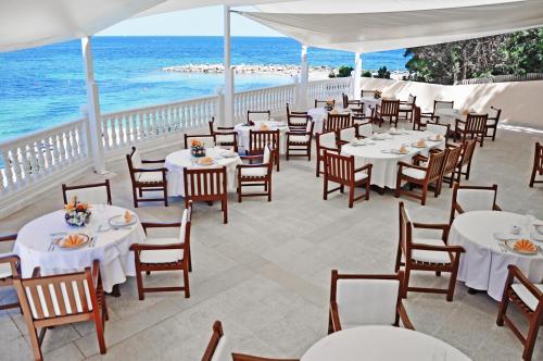 un restaurant avec des tables et des chaises blanches et l'océan dans l'établissement Grand Hotel Palladium Santa Eulalia del Río, à Santa Eulària des Riu