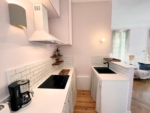 une cuisine avec comptoirs blancs et appareils électroménagers blancs dans l'établissement Suite avec grande terrasse et parc - gîte classé 4 étoiles, à Étretat