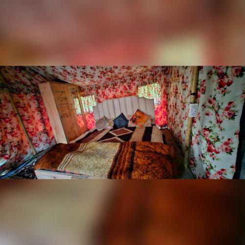 1 dormitorio con 1 cama con papel pintado con motivos florales en In the jungle camps, en Kasol