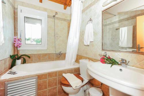 y baño con bañera, aseo y lavamanos. en Villa Rea, en Adelianos Kampos