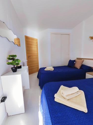 ベニドルムにあるPiso Lux Marのベッド2台、テーブル、タオルが備わる客室です。