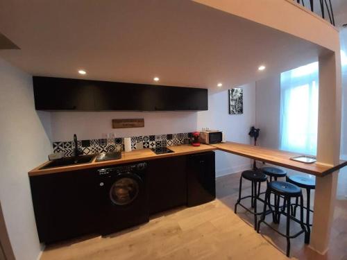 une cuisine avec un lave-linge et un comptoir avec des tabourets dans l'établissement Toulouse centre Compans Caffarelli Superbe Studio, à Toulouse