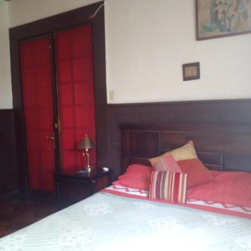 1 dormitorio con puertas rojas y 1 cama con almohadas rojas en Hostal María Luisa Bombal en Viña del Mar