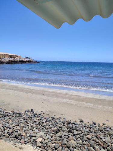 a beach with rocks on the sand and the ocean at Playgarza relax in Telde
